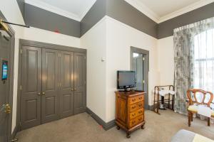 a living room with a tv on a wooden dresser at Rutland Arms Inn in Whanganui