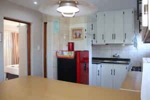 a kitchen with a red refrigerator and white cabinets at Rietjie Se Plekkie in Amanzimtoti