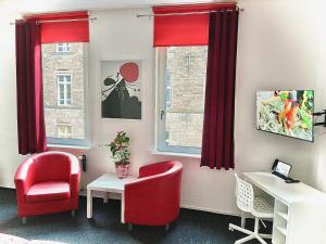 ein Zimmer mit roten Stühlen, einem Schreibtisch und einem Fenster in der Unterkunft Hotel Tusculum in Marburg an der Lahn