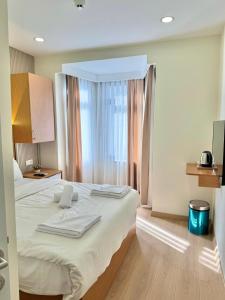 Un dormitorio con una cama con sábanas blancas y una ventana. en Royal Pera Taksim, en Estambul