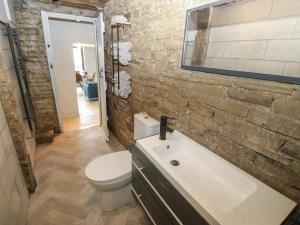 a bathroom with a white toilet and a brick wall at Myrtle Vista in Keighley