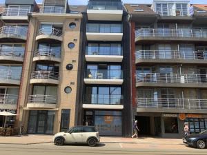 a car parked in front of a tall building at La madeleine in De Panne