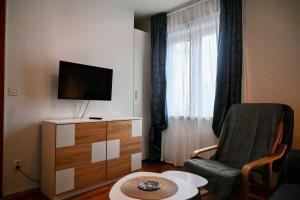 a living room with a tv and a chair and a table at Apartments Tea Pag in Pag