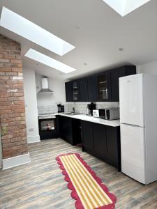 a kitchen with black cabinets and a red and yellow rug at The Newcastle Residence Cozy & Modern Flats in The Park Estate in Nottingham +86 photos