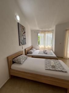two beds in a bedroom with a window at Villa Mia apartments in Sutomore