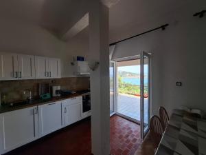 a kitchen with white cabinets and a view of the ocean at Apartment Lukovo - Puskaric in Lukovo