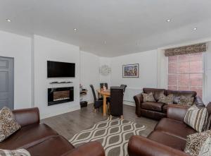 a living room with leather couches and a table at 4A City Cottages in Chester