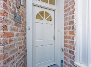a white door in a brick wall at 4A City Cottages in Chester +18 photos