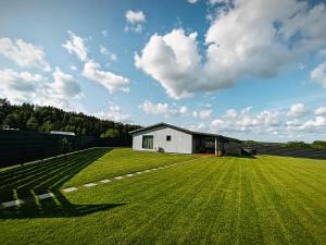a large grass field with a white building in the background at Sodyba Miško pakrašty in Gailiūnai