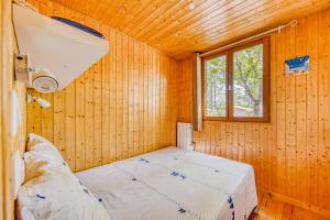 ein Bett in einem Holzzimmer mit Fenster in der Unterkunft Bungalow Californie 48 in Vendays-Montalivet