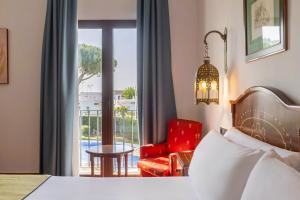 a bedroom with a bed and a chair and a window at Moon Dreams El Cortijo in Matalascañas
