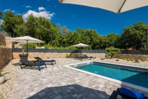 a swimming pool with chairs and umbrellas next to a pool at Kuća za odmor TARA & LANA I in Kornić