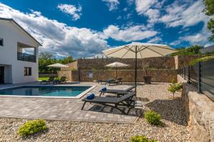 a patio with an umbrella and a swimming pool at Kuća za odmor TARA & LANA I in Kornić