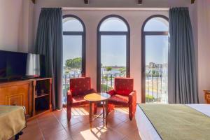 a hotel room with a bed and two chairs and a television at Moon Dreams El Cortijo in Matalascañas