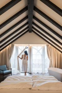 a woman standing in a bedroom looking out the window at Bella Posta Premium Apartments in Soprabolzano
