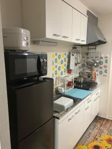 a kitchen with a black refrigerator and white cabinets at MINPAKUx櫻花 in Osaka
