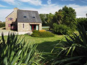 a stone house with a red door in a yard at Maison de charme à Porspoder Piscine extérieure, proche plages & calme in Porspoder
