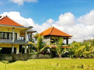 a house with an orange roof and some palm trees at Semanggi Cottage in Ubud