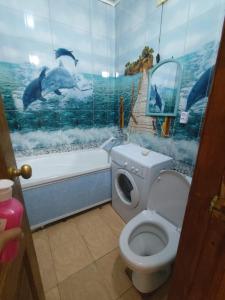 a bathroom with a toilet and a bath tub with dolphins on the wall at Квартира in Aktobe