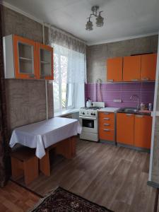 a kitchen with orange and purple cabinets and a stove at Квартира in Aktobe