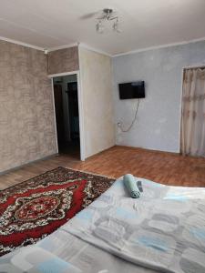 a bedroom with a bed and a tv on the wall at Квартира in Aktobe