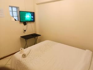 a bedroom with a bed and a tv on the wall at TRIANGLE STARS Guest House in Kempton Park