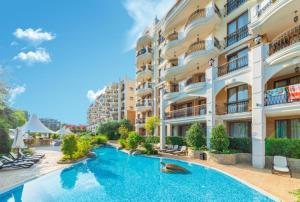 a hotel with a swimming pool in front of a building at Harmony Suites Grand Resort 16 in Sunny Beach