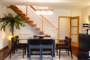 a dining room with a table and chairs and a staircase at Fão Apart in Fão