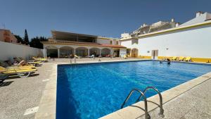 une piscine avec des chaises et un bâtiment dans l'établissement Pine Cliffs by Check-in Portugal, à Albufeira