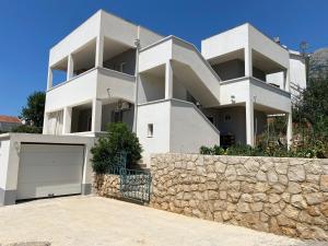 a white apartment building with a stone wall at Apartmani AMAN in Dobra Voda
