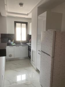 a white kitchen with a refrigerator and a window at Apart s2 ain zaghouen la marsa in La Marsa