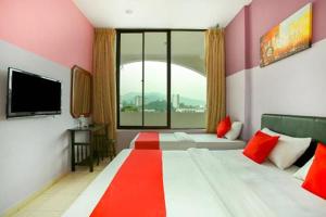 a hotel room with two beds and a large window at Feringghi Stay Iinn in Batu Ferringhi