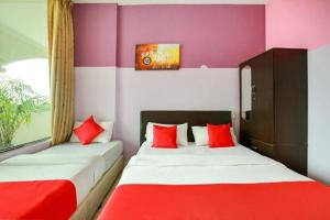 two beds in a room with red and white at Feringghi Stay Iinn in Batu Ferringhi