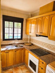 a kitchen with wooden cabinets and a sink at Juweeltje van Hondon, met groot zwembad en rust in Hondón de las Nieves