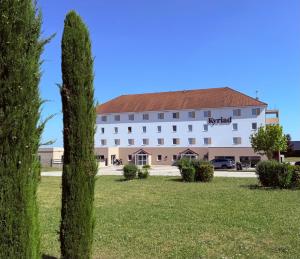 ディジョンにあるKyriad Dijon Sud - Longvicの手前に木が植えられた白い大きな建物