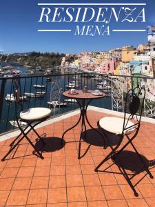 a table and chairs on a balcony with a view of the water at RESIDENZA MENA marina CORRICELLA in Procida