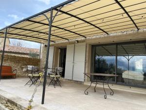 un pergolato sopra un patio con tavolo e sedie di Maison dans un hameau avec piscine a Gordes