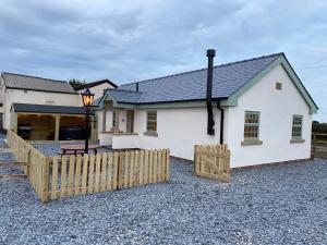 a white house with a wooden fence in front of it at Pointer Cottage in Preesall