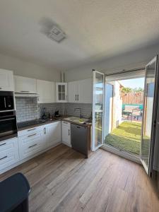 a kitchen with white cabinets and a large sliding glass door at La belle aventure in Rivesaltes +19 photos
