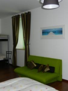 ein grünes Sofa im Wohnzimmer mit Vorhängen in der Unterkunft Hôtel Terminus in Pruntrut