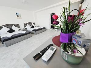a living room with a table with a remote control and flowers at LA PLAYA - Camere pe plaja cu sezlong gratuit in Eforie Nord