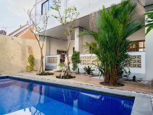 a swimming pool in front of a house with trees at Firdaus Studio Apartments in Dalung