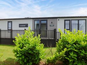 un mobil-home avec une clôture et des buissons dans l'établissement Hazelnut Lodge, à Chipping Norton