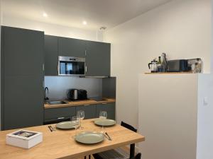 a kitchen with a wooden table with plates and wine glasses at Gaïa - Maison intra-muros 3 chambres in Avignon