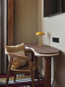 a wooden table and a chair with a table and a television at Hôtel Mercedes in Paris