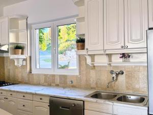 a kitchen with white cabinets and a sink and a window at Indigo Cavtat Apartments in Cavtat +109 photos