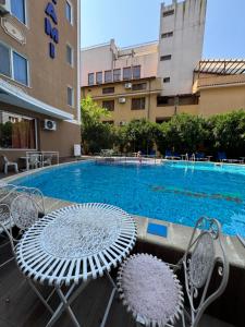 a pool with two chairs and a table next to a building at SUNRISE Suites in Sunny Beach