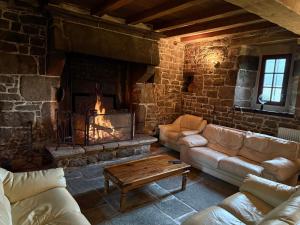 ein Wohnzimmer mit Kamin, Sofas und Tisch in der Unterkunft Splendide MANOIR - Proche plages - 4 chambres - 3sdb - 8 pers - WIFI in Plounérin
