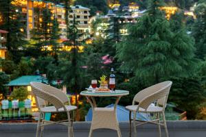 ダラムシャーラーにあるGolden Rock, Dharamshala - AM Hotel Kollectionの椅子2脚、テーブル、ドリンク付きのバルコニー