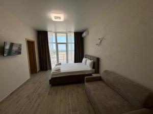 a bedroom with a bed and a couch and a window at Milos Hotel in Zatoka